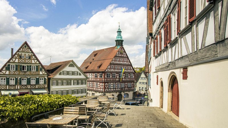 A view of historic half-timbered houses in Backnang. In the foreground are empty seats; in the background is a blue sky with clouds., &copy; SMG Stuttgart Marketing GmbH - Sarah Schmid