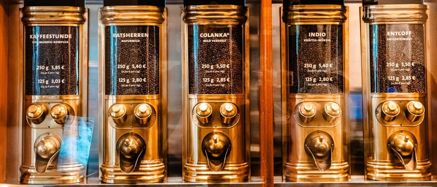 Fünf goldene Kaffeespender mit verschiedenen Kaffeesorten: Kaffeestunde, Ratsherren, Colanka, Indio, Entcoff. Preise und Mengen sind angegeben., © Stuttgart Marketing GmbH - Sarah Schmid