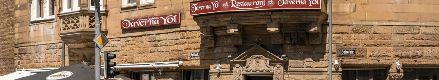 Historic building with restaurant Taverna Yol, outdoor seating, street signs and traffic lights. Sunny day, flowers in windows., &copy; SMG Stuttgart Marketing GmbH - Sarah Schmid