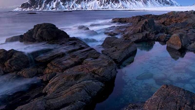 Snow-covered mountains in the background, rocky coastline in the foreground, sea and dramatic sky at sunset., &copy; Theaterhaus Stuttgart e.V.
