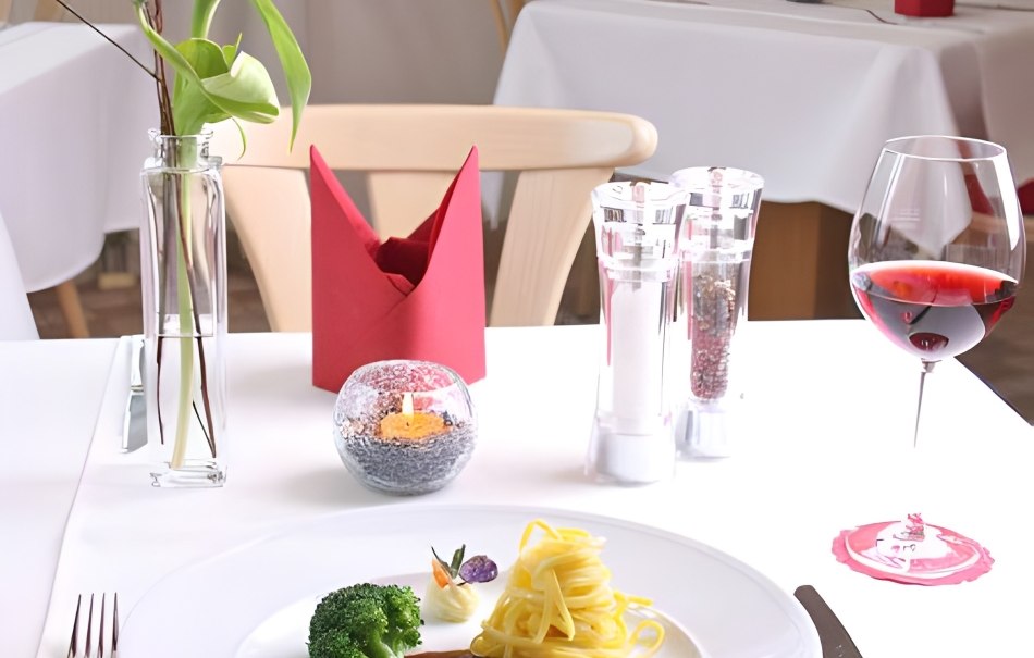An elegantly laid table in a restaurant with plate, cutlery, wine glass, candle and flower. The dish consists of meat, pasta and broccoli., © Hotel Neuwirtshaus An elegantly laid table in a restaurant with plate, cutlery, wine glass, candle and flower. The dish consists of meat, pasta and broccoli., © Hotel Neuwirtshaus