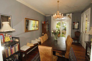 Elegant dining room with large wooden table, upholstered chairs, mirror, chandelier and view of the garden., &copy; Elsbeth Koch
