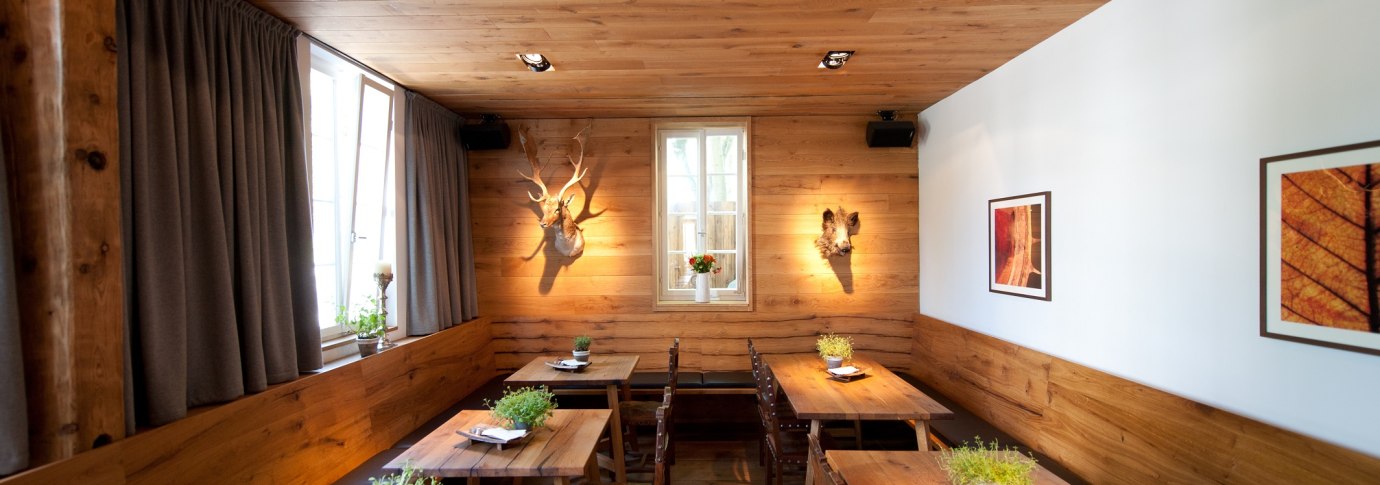 Ein gem&uuml;tliches Restaurant mit Holztischen, Pflanzen auf den Tischen und dekorativen Elementen an den W&auml;nden. Holzw&auml;nde und -decke schaffen eine warme Atmosph&auml;re., &copy; Ruthenberg&Schlatter GbR
