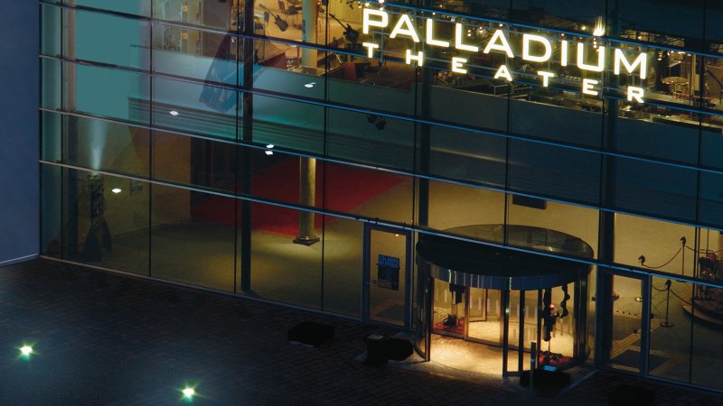Nachtaufnahme des beleuchteten Eingangs des Palladium Theaters mit Glasfassade und rotem Teppich., &copy; Stage Entertainment
