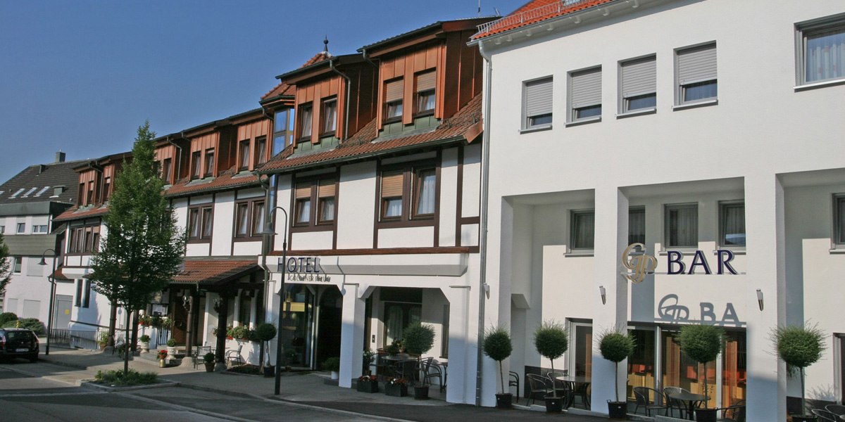The facade of the Goldener Pflug hotel and restaurant, featuring a bar and outdoor seating area, surrounded by trees and plants., &copy; Hotel & Restaurant Goldener Pflug