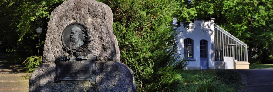 Memorial stone for Gottlieb Daimler in a green park, on the right a white building with glass windows., &copy; Stuttgart-Marketing GmbH Achim Mende