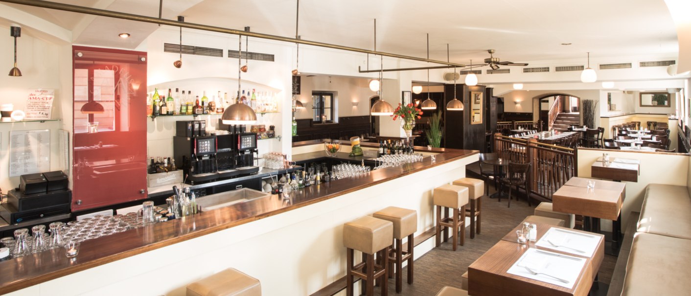 Stylish restaurant with bar, wooden furniture and laid tables. Bright lighting and cozy atmosphere., © Amadeus, Stuttgart Stylish restaurant with bar, wooden furniture and laid tables. Bright lighting and cozy atmosphere., © Amadeus, Stuttgart