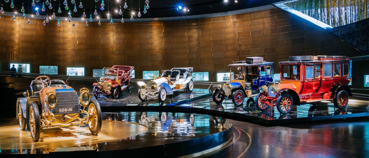 Historische Autos in einer Ausstellung im Mercedes-Benz Museum, beleuchtet unter einer Decke mit hängenden Glaskugeln., © Stuttgart-Marketing GmbH, Thomas Niedermüller