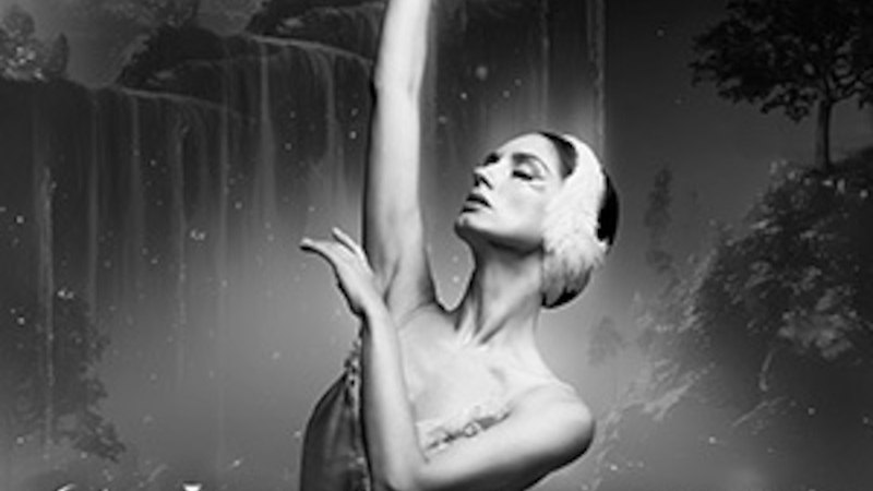 Eine Ballerina in einem Schwanenkost&uuml;m posiert elegant vor einem dunklen, mystischen Hintergrund mit Waldsilhouette. Der Titel 'Schwanensee' ist sichtbar., &copy; Konstantin Rain be.entertained