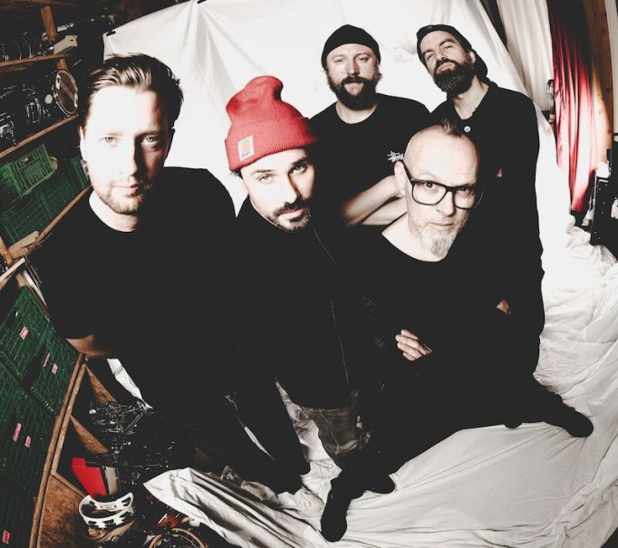 F&uuml;nf M&auml;nner stehen in einem Raum mit wei&szlig;en Vorh&auml;ngen. Einer tr&auml;gt eine rote M&uuml;tze. Die Gruppe wirkt l&auml;ssig und selbstbewusst., &copy; Theaterhaus Stuttgart e.V.