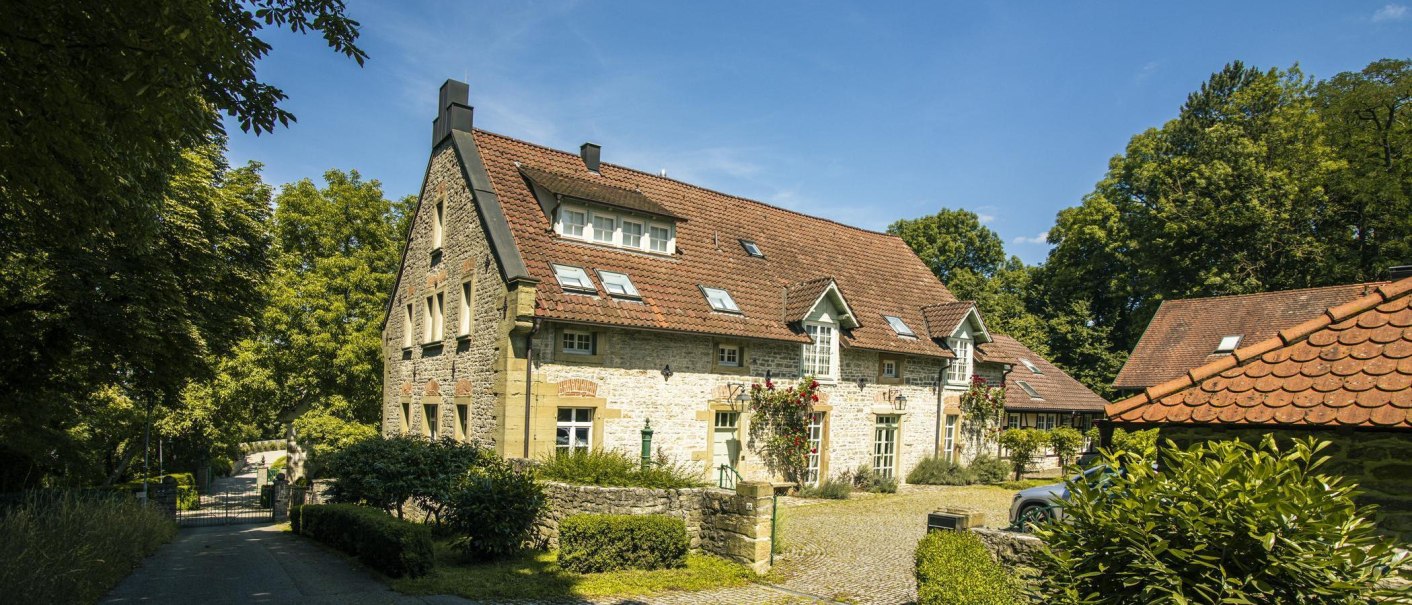 A charming, historic building with a red-tiled roof and blooming roses along the facade, surrounded by lush greenery and a paved path., &copy; SMG Stuttgart Marketing GmbH - Sarah Schmid