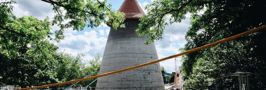 Ein Winkelturm mit rotem Dach umgeben von Bäumen, unter einem blauen Himmel. Menschen gehen auf einem gepflasterten Weg., © tmbw, Susi Maier