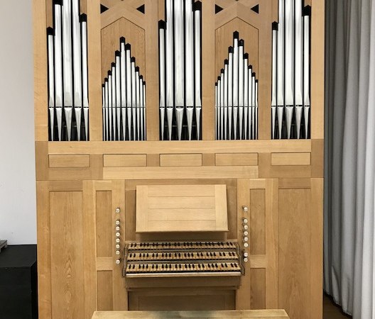Große Holzorgel mit Pfeifen und Tastatur, auf einem Holzboden stehend. Die Orgel hat ein schlichtes, geometrisches Design., © Staatliche Hochschule für Musik und Darstellende Kunst Große Holzorgel mit Pfeifen und Tastatur, auf einem Holzboden stehend. Die Orgel hat ein schlichtes, geometrisches Design., © Staatliche Hochschule für Musik und Darstellende Kunst