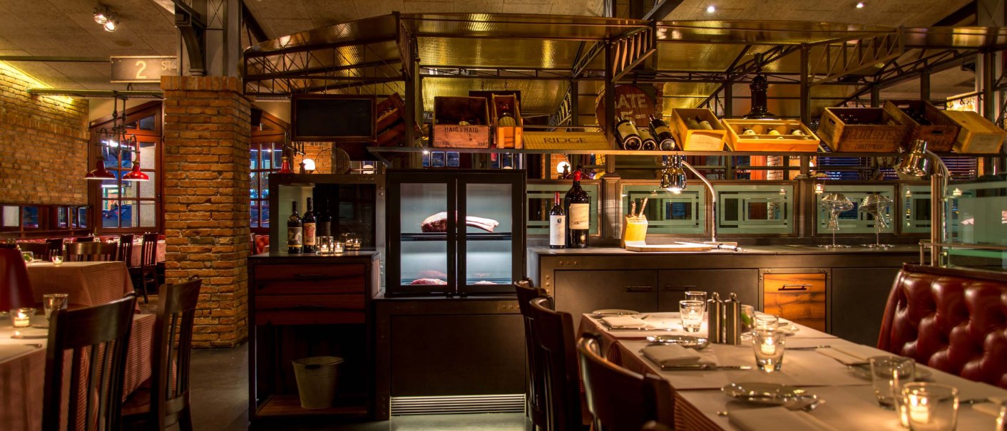 Stylish restaurant with brick walls, laid tables and bottles of wine. Warm light creates a cozy atmosphere., © ©Pier 51 Stylish restaurant with brick walls, laid tables and bottles of wine. Warm light creates a cozy atmosphere., © ©Pier 51