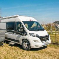 A motorhome is parked on a pitch in Beuren. Chairs and a table are set up next to it. Trees and a building with solar panels can be seen in the background., © Stuttgart-Marketing GmbH, Sarah Schmid A motorhome is parked on a pitch in Beuren. Chairs and a table are set up next to it. Trees and a building with solar panels can be seen in the background., © Stuttgart-Marketing GmbH, Sarah Schmid