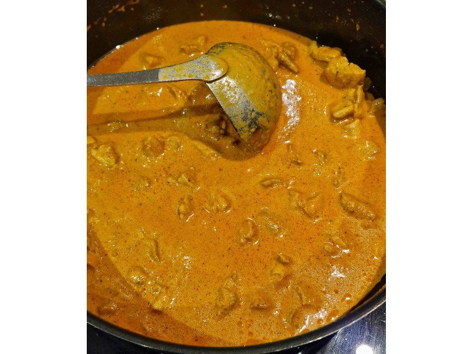 Ein Topf mit cremigem, orangefarbenem Curry und Fleischst&uuml;cken. Eine Kelle liegt in der So&szlig;e, bereit zum Servieren., &copy; Kultweine-Kochwelten-Kunst&uuml;cke - Kochschule Sonja Lenz