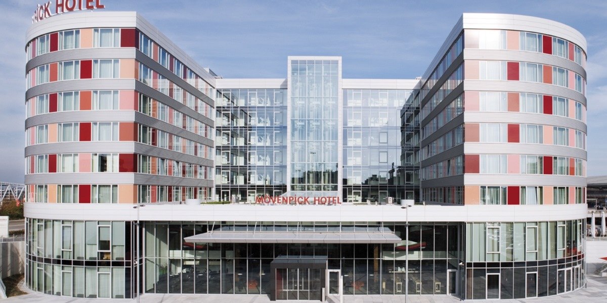 Das Mövenpick Hotel Stuttgart Airport zeigt eine moderne Glasfassade mit abgerundeten Ecken und roten Akzenten., © Mövenpick Hotel Stuttgart Airport Das Mövenpick Hotel Stuttgart Airport zeigt eine moderne Glasfassade mit abgerundeten Ecken und roten Akzenten., © Mövenpick Hotel Stuttgart Airport