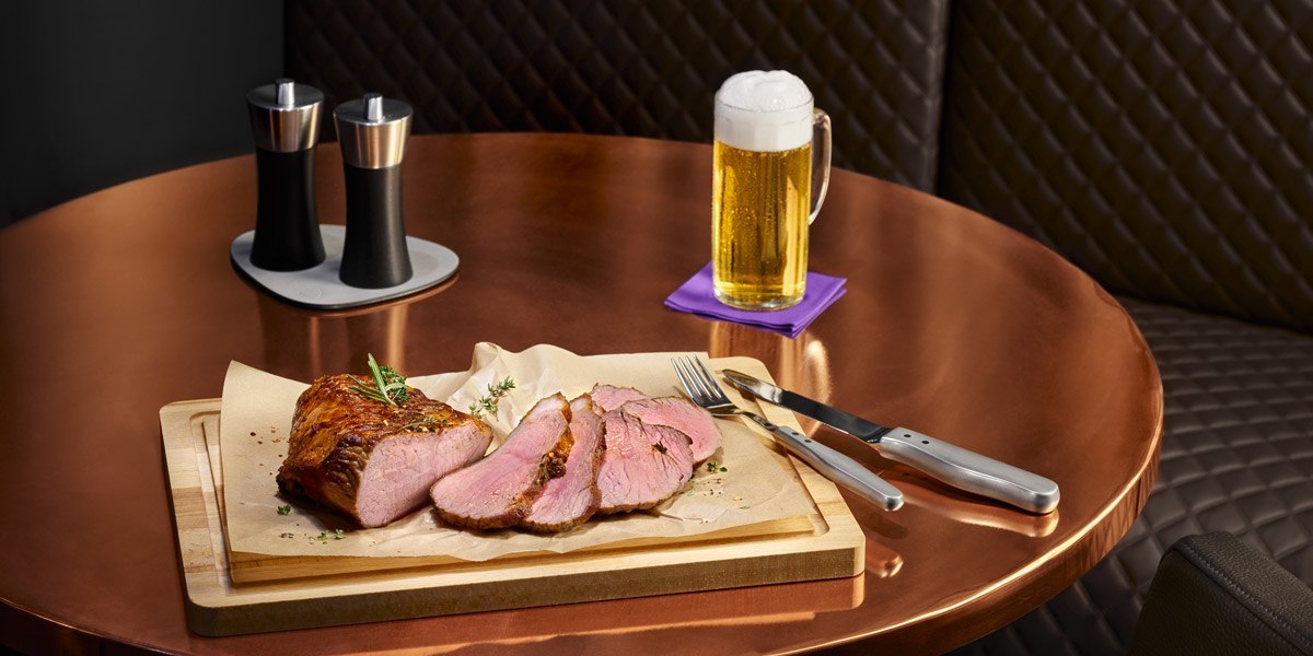 A table with sliced meat on a wooden board, cutlery, salt and pepper shakers and a beer mug., © Jaz Hotel Stuttgart A table with sliced meat on a wooden board, cutlery, salt and pepper shakers and a beer mug., © Jaz Hotel Stuttgart