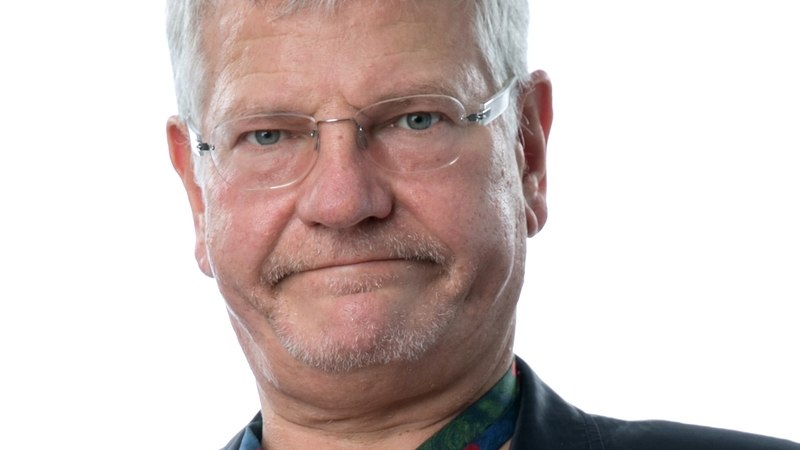 Ein Mann mit grauen Haaren und Brille tr&auml;gt einen Anzug und eine bunte Krawatte. Der Hintergrund ist wei&szlig;., &copy; Renitenztheater Stuttgart e.V.