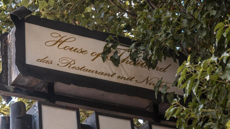 Ein Schild mit der Aufschrift 'House of Thailand, das Restaurant mit Niveau', umgeben von gr&uuml;nen Bl&auml;ttern., &copy; Stuttgart Marketing GmbH, Sarah Schmid