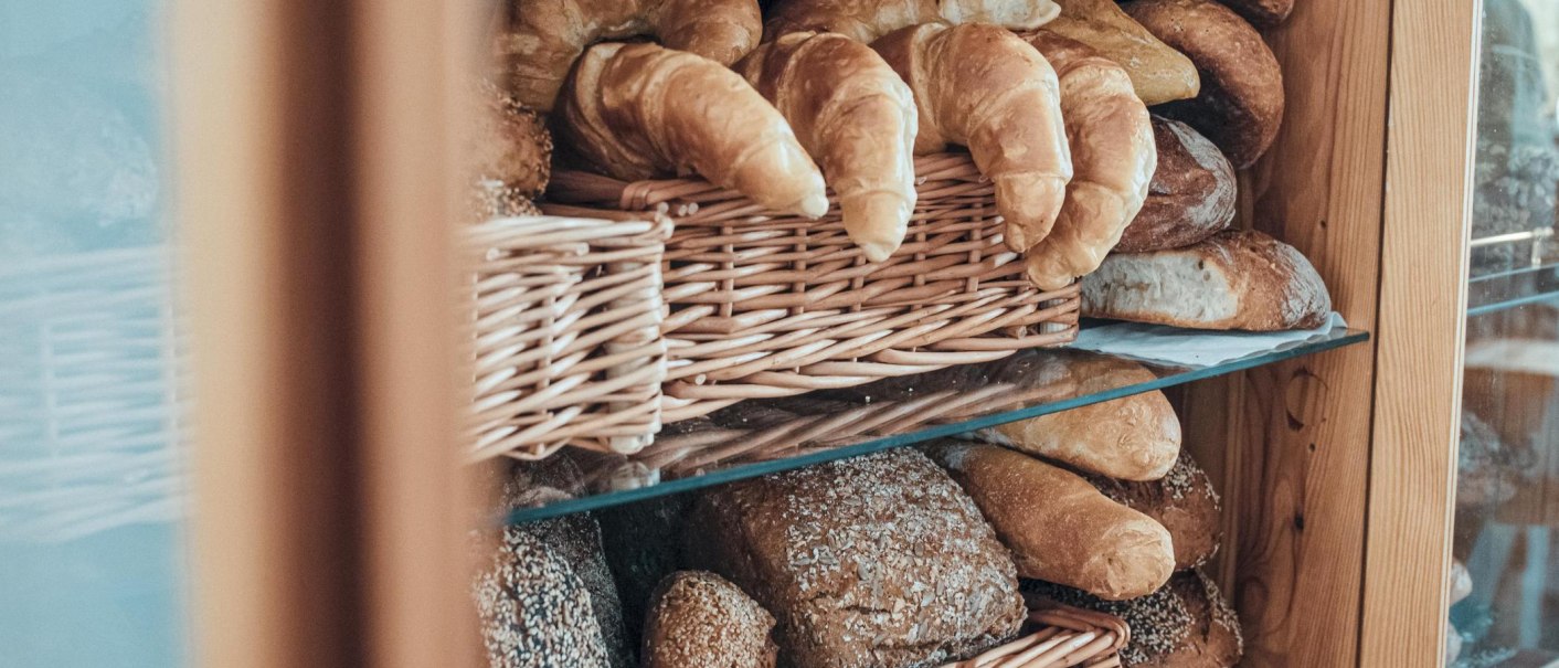 Ein Regal mit Körben voller Croissants und Brote in einem Holzschrank., © Raupe Immersatt e.V., Stuttgart