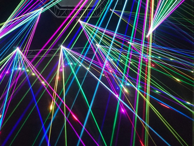 Bunte Laserstrahlen durchziehen einen dunklen Raum und erzeugen ein lebendiges, futuristisches Muster., &copy; Cool-Tours StattReisen