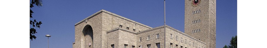 Stuttgart Central Station with its striking clock tower and Mercedes star, surrounded by cars and trees, under a clear blue sky., &copy; Stuttgart-Marketing GmbH
