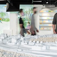 Ein Mann betrachtet ein Architekturmodell in einer Ausstellung. Im Hintergrund sind Illustrationen und Notizen an der Wand zu sehen., © Stadt Stuttgart / Dominique Brewing Ein Mann betrachtet ein Architekturmodell in einer Ausstellung. Im Hintergrund sind Illustrationen und Notizen an der Wand zu sehen., © Stadt Stuttgart / Dominique Brewing