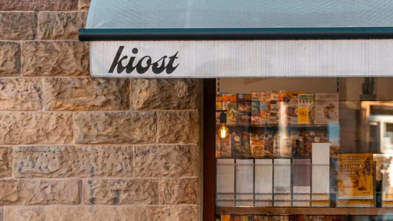 Ein Kiosk mit der Aufschrift 'kiost' zeigt Zeitschriften im Schaufenster. Die Steinwand und das Licht schaffen eine gem&uuml;tliche Atmosph&auml;re., &copy; Stuttgart-Marketing GmbH, Sarah Schmid