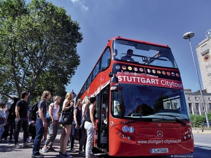 Roter Doppeldeckerbus der Stuttgart Citytour, Menschen steigen ein. Der Bus steht an einer Haltestelle, im Hintergrund Bäume und ein Gebäude., © SMG, Pierre Polak Roter Doppeldeckerbus der Stuttgart Citytour, Menschen steigen ein. Der Bus steht an einer Haltestelle, im Hintergrund Bäume und ein Gebäude., © SMG, Pierre Polak