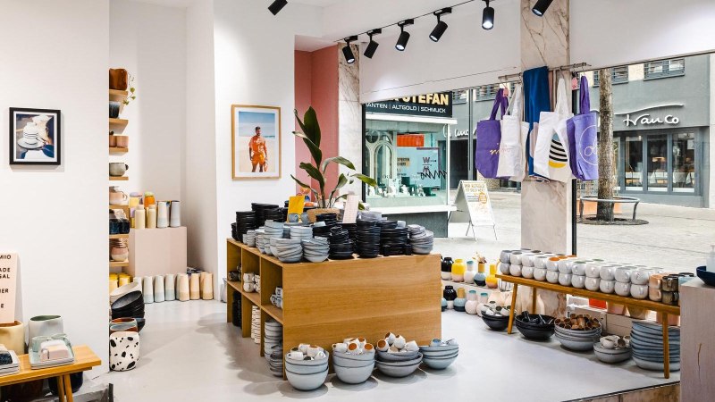 Ceramics store with shelves full of crockery, cups and vases. Pictures and bags hang on the wall. You can see a street through the shop window., © by Canto