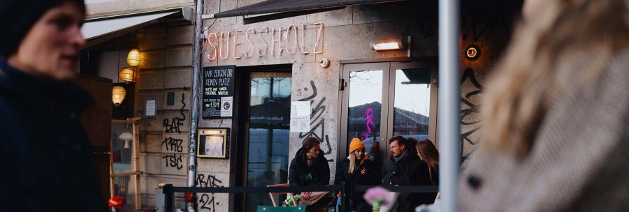 Au&szlig;enansicht des Caf&eacute;s 'Suessholz' im Leonhardsviertel. Menschen sitzen drau&szlig;en, unterhalten sich. Graffiti an den W&auml;nden, Neonlicht im Fenster., &copy; Stuttgart-Marketing GmbH, Alwin Maigler