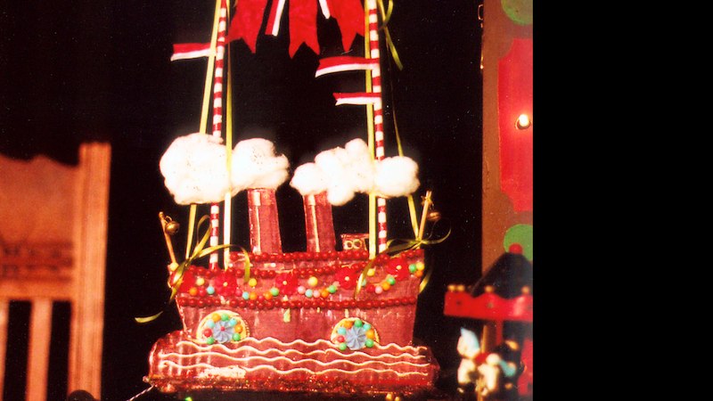 Ein Schokoladenschiff mit bunten Verzierungen und Segeln, umgeben von festlicher Dekoration. Es wirkt wie ein kunstvolles Dessert., © FITZ Das Theater animierter Formen