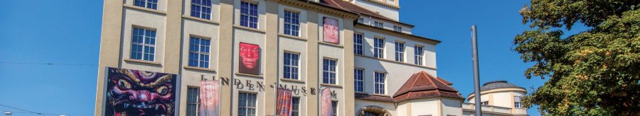 The Linden Museum in Stuttgart in sunny weather. Posters and a large silver sphere can be seen in front of the building. People stroll past., © © Stuttgart-Marketing GmbH