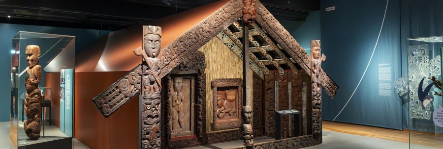Exhibition in the Linden-Museum Stuttgart with an artistically carved Maori house and figures. The exhibits are richly decorated and detailed., © SMG Stuttgart Marketing GmbH - Sarah Schmid