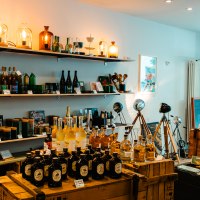 A cozy store with shelves full of bottles, lamps and decorative items. Wooden crates and tripod lamps complete the ambience., &copy; Sarah Schmid