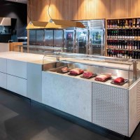 Modern meat store with a counter displaying pieces of meat. A shelf with wine bottles in the background. Wood paneling and stylish furnishings., &copy; Meat Club, Stuttgart
