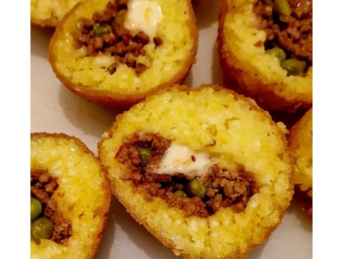 Gefüllte Reisbällchen mit Fleisch und Erbsen, goldbraun frittiert, aufgeschnitten und auf einem Teller angerichtet., © Kultweine-Kochwelten-Kunstücke - Kochschule Sonja Lenz Gefüllte Reisbällchen mit Fleisch und Erbsen, goldbraun frittiert, aufgeschnitten und auf einem Teller angerichtet., © Kultweine-Kochwelten-Kunstücke - Kochschule Sonja Lenz