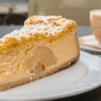 Ein Stück Kuchen mit Puderzucker auf einem Teller, daneben eine Tasse Kaffee auf einem Tisch im Café Schurr., © SMG, Sarah Schmid Ein Stück Kuchen mit Puderzucker auf einem Teller, daneben eine Tasse Kaffee auf einem Tisch im Café Schurr., © SMG, Sarah Schmid