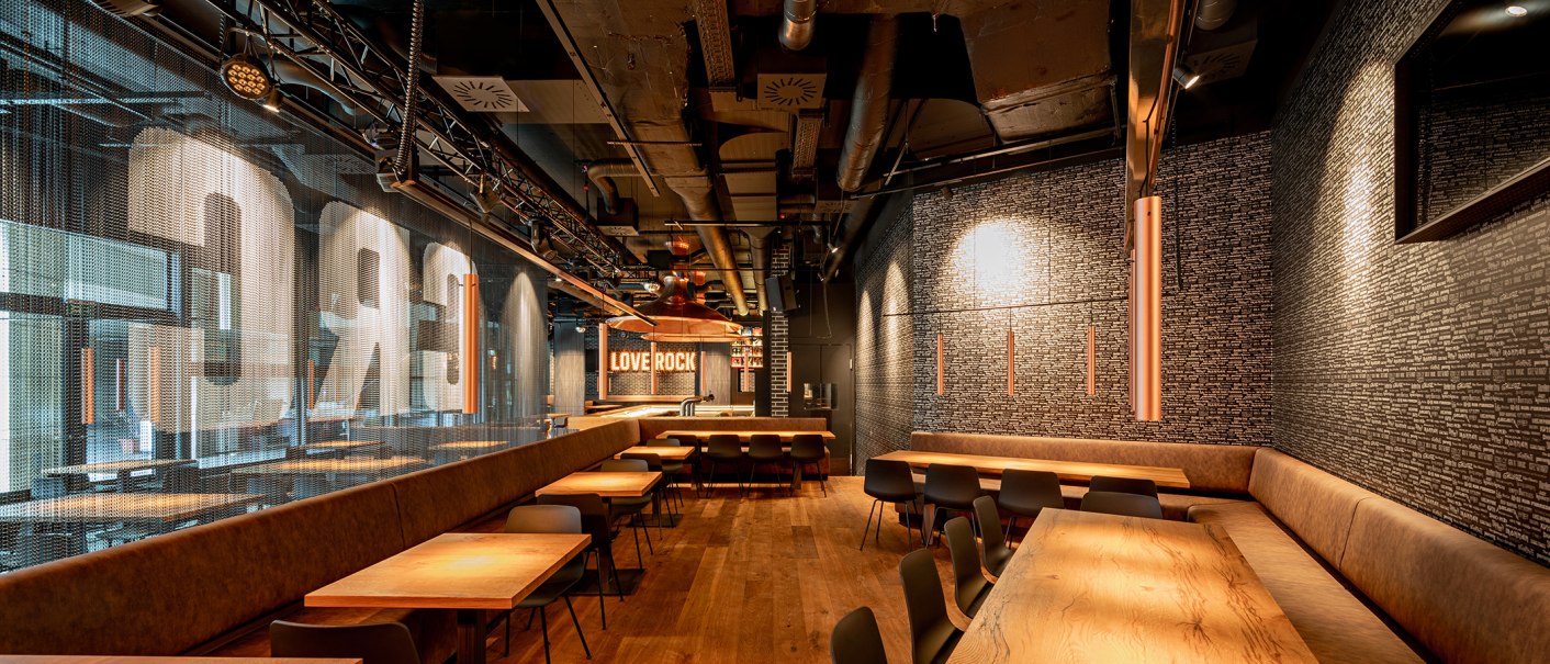 Modern café with wooden tables, upholstered benches and the lettering 'LOVE ROCK' on the wall., © Maks Richter Modern café with wooden tables, upholstered benches and the lettering 'LOVE ROCK' on the wall., © Maks Richter