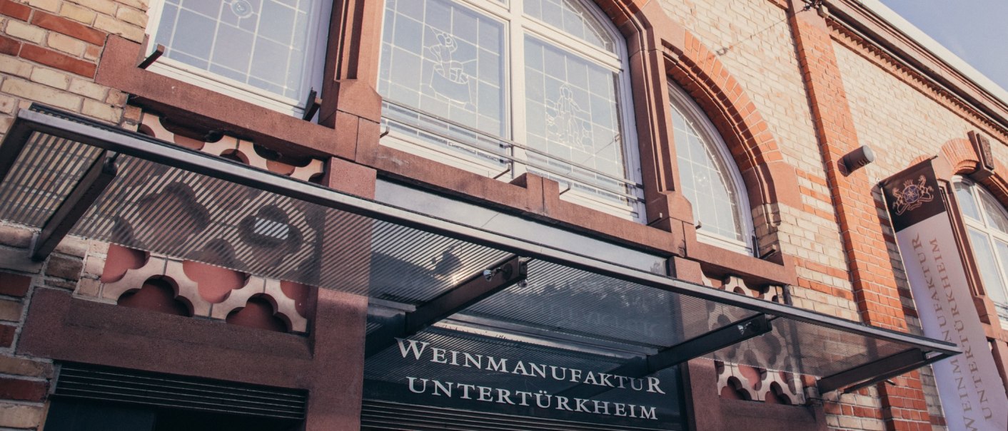 Façade of the Untertürkheim wine manufactory with glass canopy, lettering and decorative windows., © Weinmanufaktur Untertürkheim Façade of the Untertürkheim wine manufactory with glass canopy, lettering and decorative windows., © Weinmanufaktur Untertürkheim