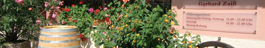 Entrance to the Besenwirtschaft Gerhard Zai&szlig; with flowering plants, a wine barrel and a sign with opening hours., &copy; Simone Mack