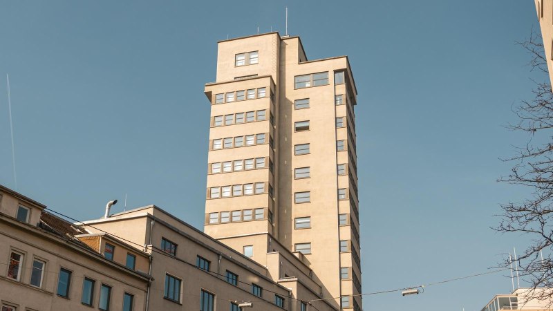 Der Tagblatt-Turm in Stuttgart ragt in den blauen Himmel, umgeben von älteren Gebäuden. Ein Kondensstreifen zieht sich durch den Himmel., © Stuttgart Marketing GmbH, Sarah Schmid Der Tagblatt-Turm in Stuttgart ragt in den blauen Himmel, umgeben von älteren Gebäuden. Ein Kondensstreifen zieht sich durch den Himmel., © Stuttgart Marketing GmbH, Sarah Schmid