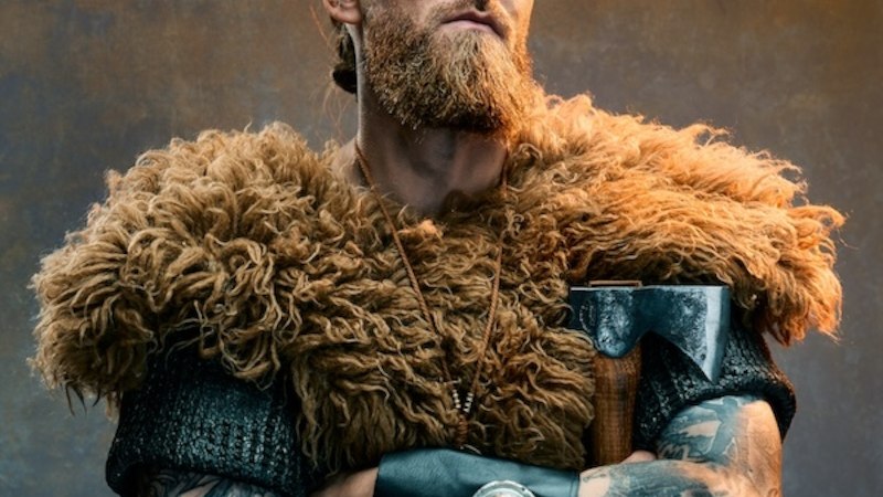 Ein Mann in Wikingerkleidung mit Fellumhang, Bart und Tattoos hält eine Axt. Er hat einen intensiven Blick und verschränkte Arme., © Renitenztheater Stuttgart e.V. Ein Mann in Wikingerkleidung mit Fellumhang, Bart und Tattoos hält eine Axt. Er hat einen intensiven Blick und verschränkte Arme., © Renitenztheater Stuttgart e.V.