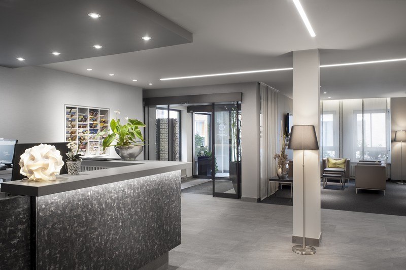 A modern hotel reception area with a stylish desk, plants, and an inviting seating area in the background., &copy; TOMAS