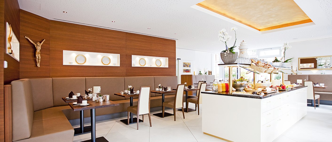 Ein heller Frühstücksraum mit modernem Design, Buffet und gemütlichen Sitzbereichen. Holzwände und dekorative Elemente schaffen eine einladende Atmosphäre., © Hotel Krone