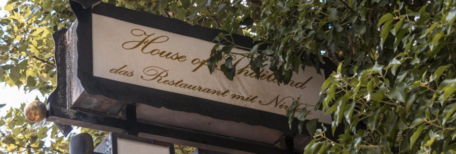 Ein Schild mit der Aufschrift 'House of Thailand, das Restaurant mit Niveau', umgeben von gr&uuml;nen Bl&auml;ttern., &copy; Stuttgart Marketing GmbH, Sarah Schmid