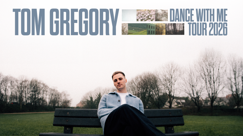 Ein Mann sitzt entspannt auf einer Parkbank, w&auml;hrend im Hintergrund kahle B&auml;ume zu sehen sind. Oben im Bild steht 'Tom Gregory Dance With Me Tour 2026'., &copy; links im Bild