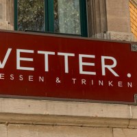 Rotes Schild mit der Aufschrift 'Vetter. Essen & Trinken' an einer Gebäudeecke aus gelben Ziegeln., © SMG, Sarah Schmid
