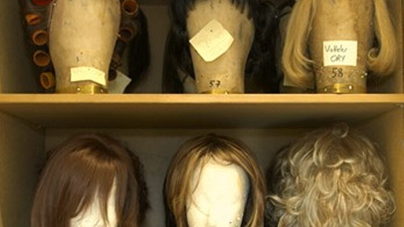 Regal mit sechs Perücken auf Styroporköpfen, einige mit Lockenwicklern. Beschriftungen auf den Köpfen sind sichtbar., © Württembergische Staatstheater Stuttgart Regal mit sechs Perücken auf Styroporköpfen, einige mit Lockenwicklern. Beschriftungen auf den Köpfen sind sichtbar., © Württembergische Staatstheater Stuttgart